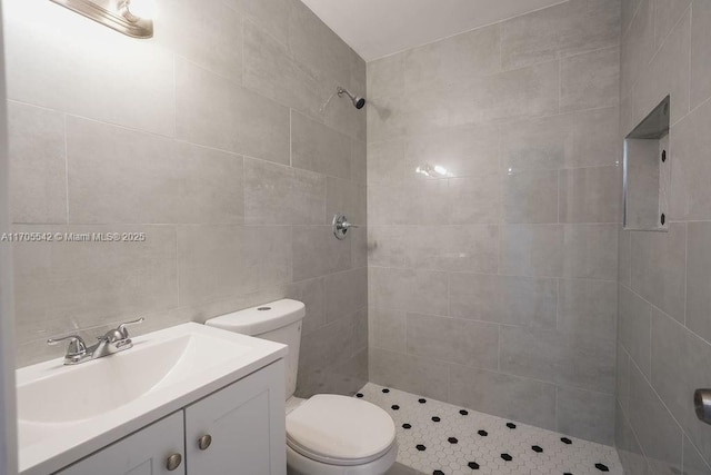 bathroom with vanity, toilet, and tiled shower