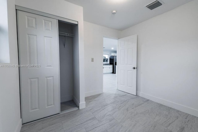 unfurnished bedroom featuring stainless steel refrigerator with ice dispenser and a closet