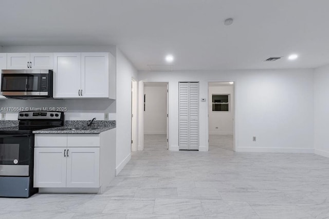 kitchen with white cabinets, appliances with stainless steel finishes, sink, and dark stone countertops