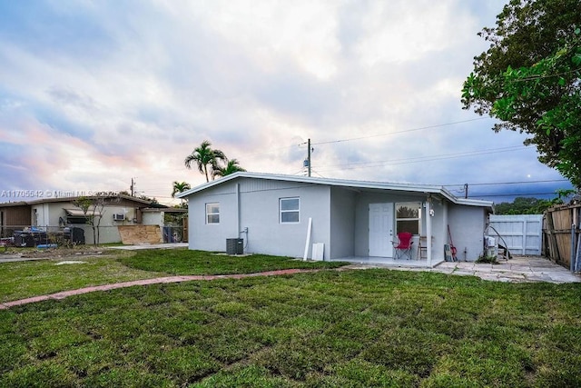 rear view of property with a lawn and cooling unit