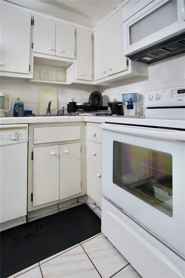 kitchen featuring white appliances, white cabinets, tasteful backsplash, tile counters, and light tile patterned flooring