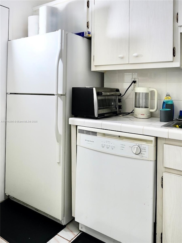 kitchen with white cabinets, white appliances, tile counters, and backsplash