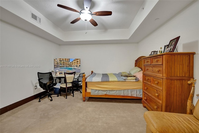 carpeted bedroom featuring a raised ceiling and ceiling fan