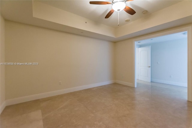 unfurnished room featuring a raised ceiling and ceiling fan