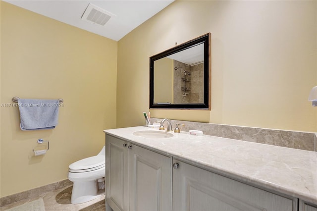 bathroom with tile patterned flooring, vanity, toilet, and tiled shower