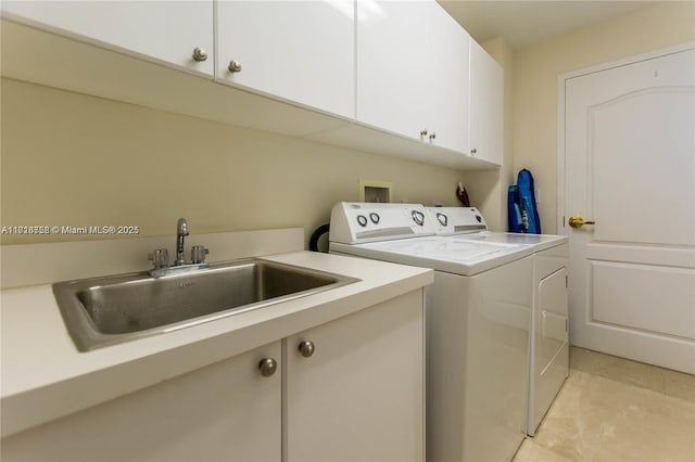 laundry area featuring washing machine and dryer, sink, light tile patterned flooring, and cabinets