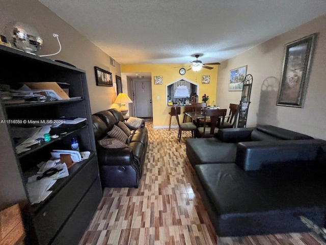 living room featuring ceiling fan and a textured ceiling