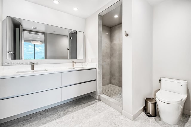 bathroom featuring a tile shower, vanity, and toilet