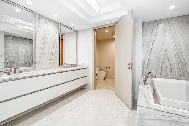 bathroom with vanity, a tub to relax in, and toilet