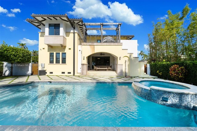 rear view of property with a balcony, a patio, a swimming pool with hot tub, and pool water feature