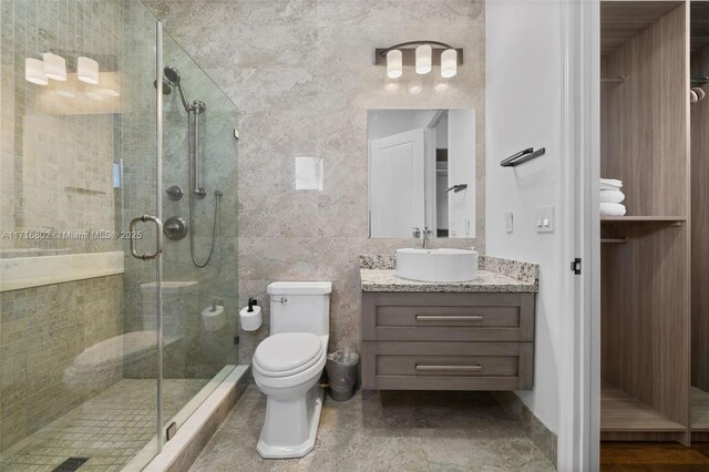 bathroom with toilet, tile walls, walk in shower, and vanity