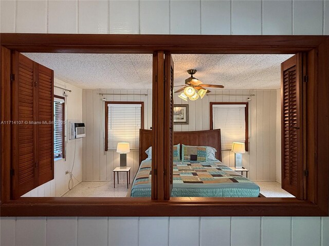 unfurnished bedroom with ceiling fan, wood walls, and a textured ceiling