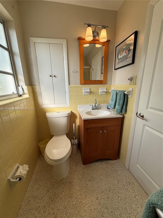 bathroom with vanity, toilet, and tile walls