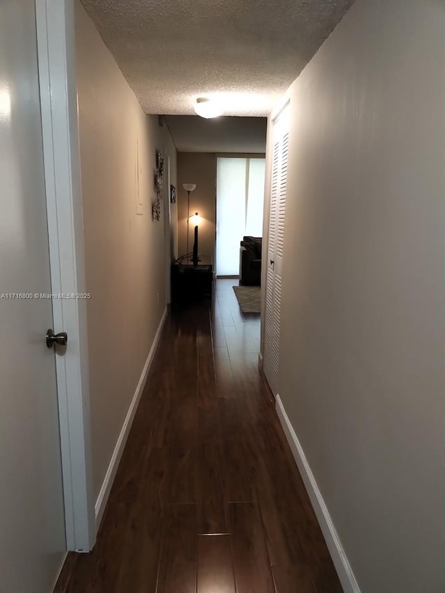 corridor featuring dark hardwood / wood-style flooring and a textured ceiling