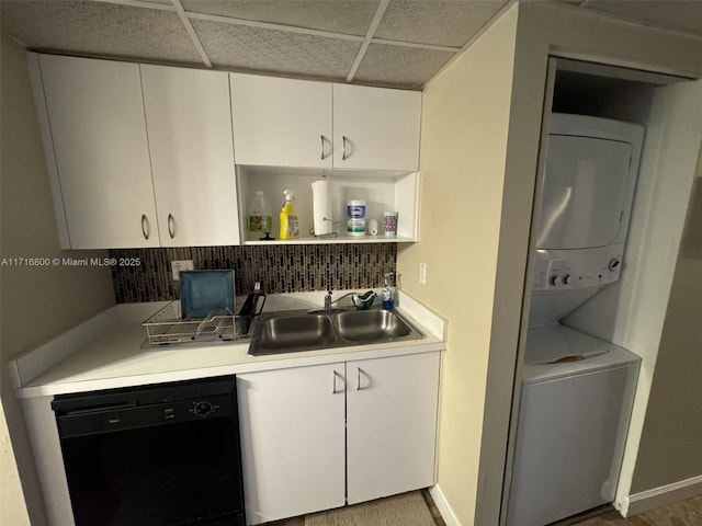 kitchen with sink, stacked washer and dryer, black dishwasher, tasteful backsplash, and white cabinetry