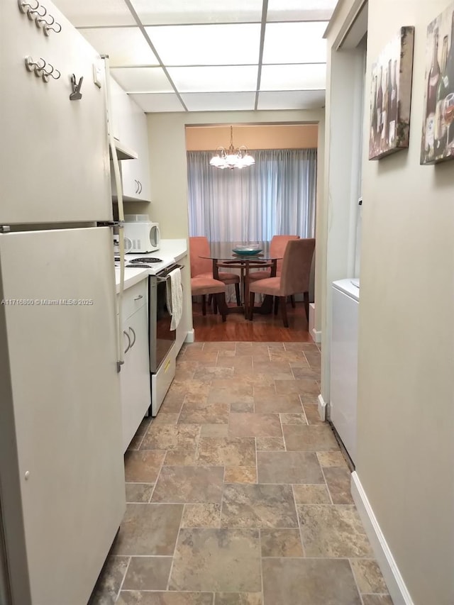 kitchen with white cabinets, decorative light fixtures, white appliances, and a chandelier