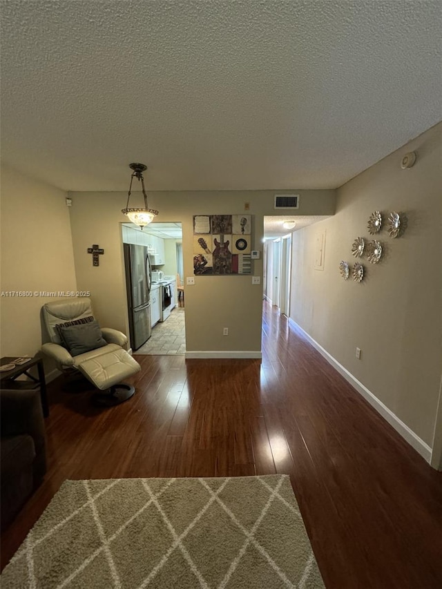 corridor with hardwood / wood-style floors and a textured ceiling