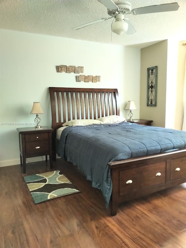 bedroom with a textured ceiling, ceiling fan, and dark wood-type flooring