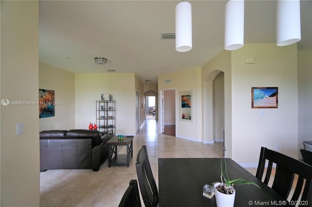 dining area with light tile patterned flooring, baseboards, visible vents, and arched walkways