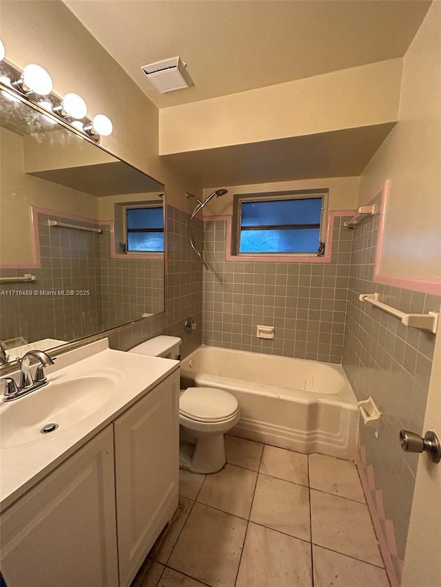 bathroom with toilet, visible vents, tile walls, tile patterned floors, and washtub / shower combination