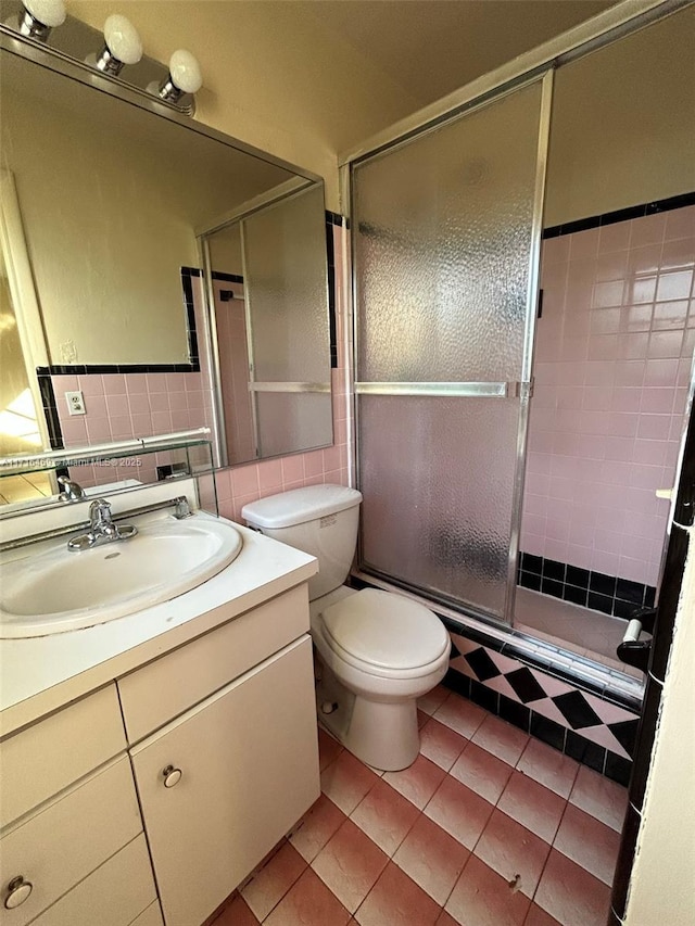 full bathroom featuring a stall shower, tile walls, toilet, vanity, and backsplash