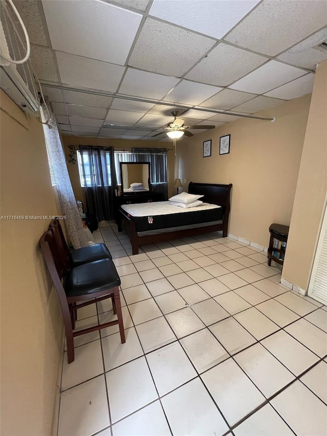 bedroom with ceiling fan, a drop ceiling, light tile patterned flooring, and baseboards