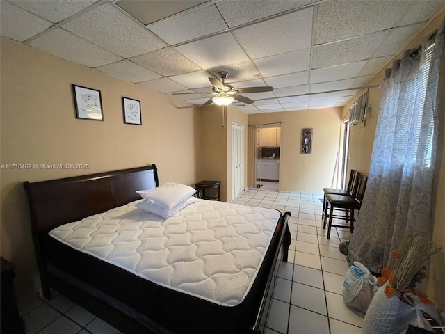 bedroom with a closet, a wall mounted AC, light tile patterned flooring, ceiling fan, and a drop ceiling