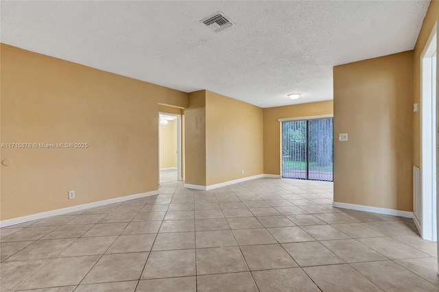 tiled empty room featuring a textured ceiling