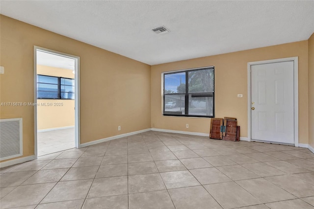 spare room with a textured ceiling and light tile patterned floors