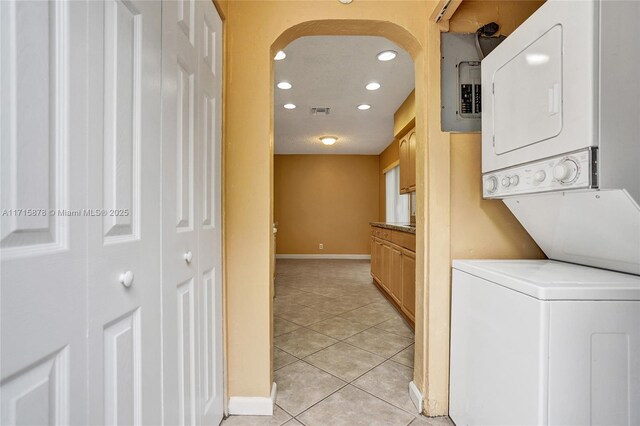 washroom with light tile patterned floors and stacked washing maching and dryer