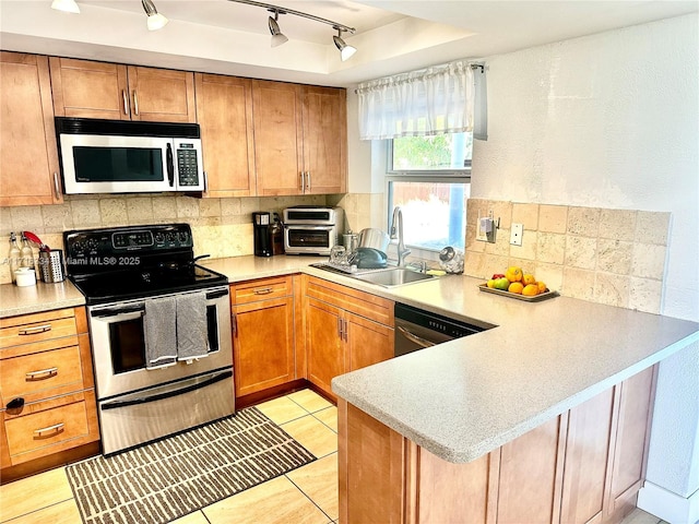 kitchen with kitchen peninsula, appliances with stainless steel finishes, track lighting, sink, and light tile patterned flooring