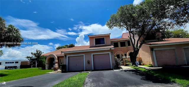 mediterranean / spanish-style home featuring a garage and a front lawn