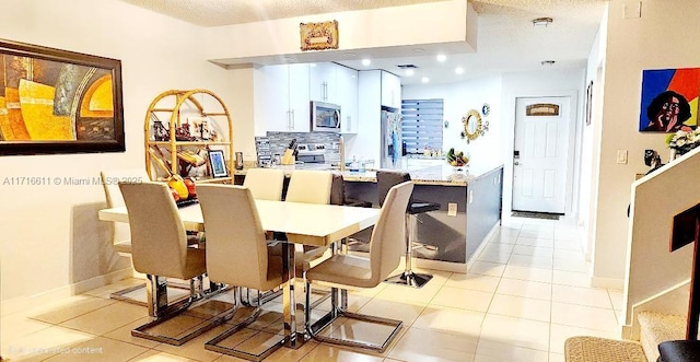 dining room featuring light tile patterned flooring and a textured ceiling