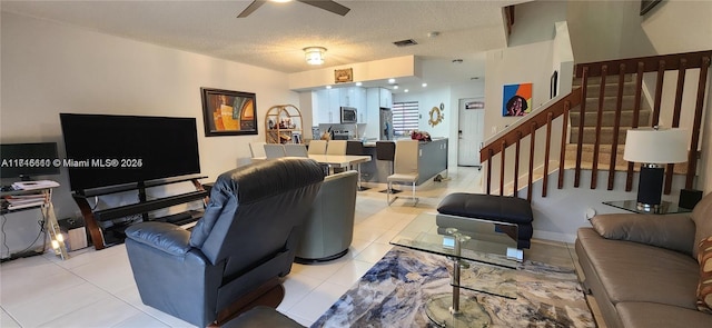 living room featuring ceiling fan, light tile patterned floors, and a textured ceiling