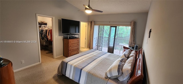 bedroom with light carpet, a walk in closet, vaulted ceiling, ceiling fan, and a closet