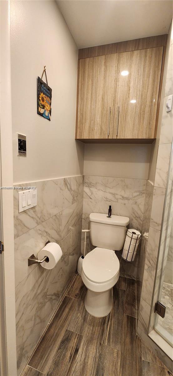 bathroom featuring toilet and tile walls