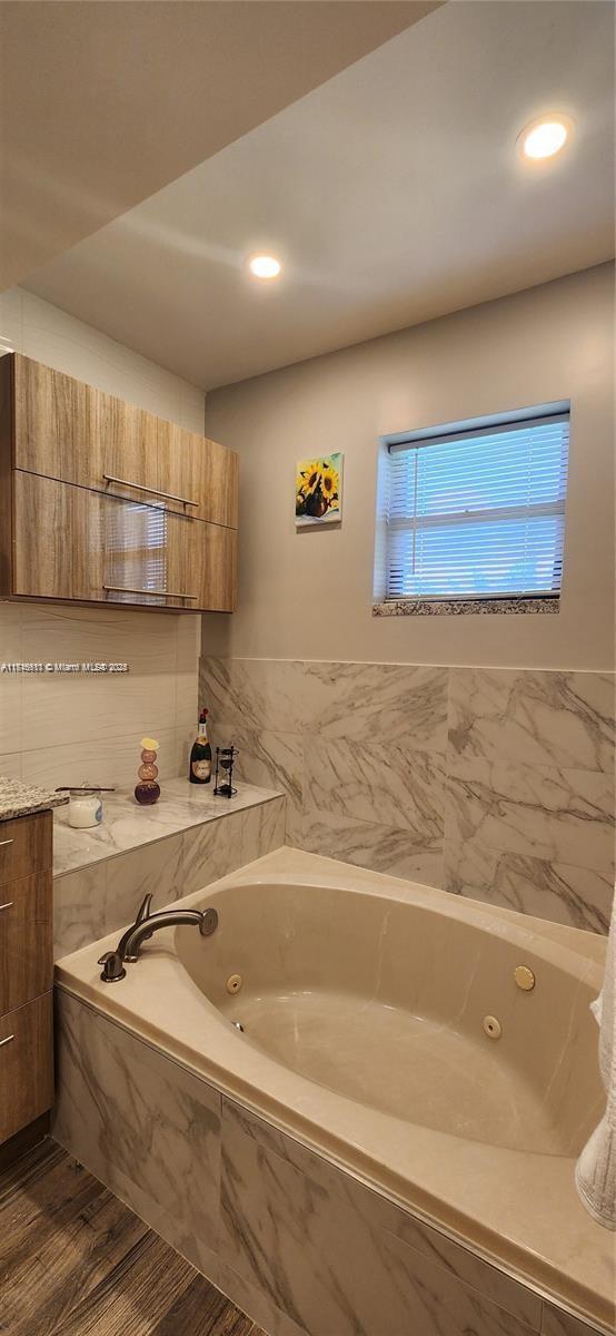 bathroom featuring wood-type flooring and tiled tub