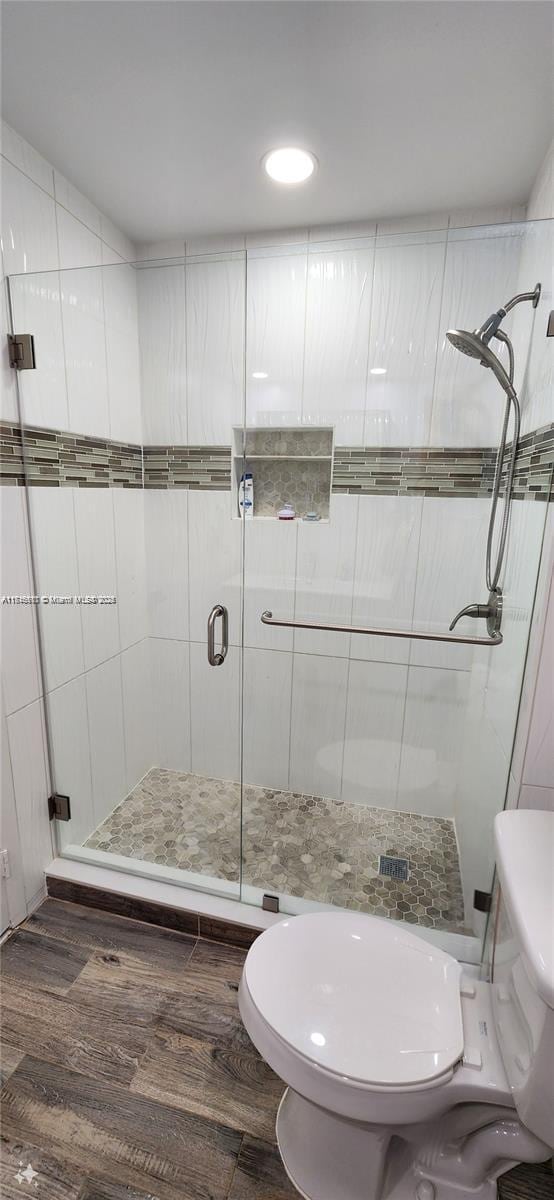 bathroom with walk in shower, toilet, and hardwood / wood-style flooring