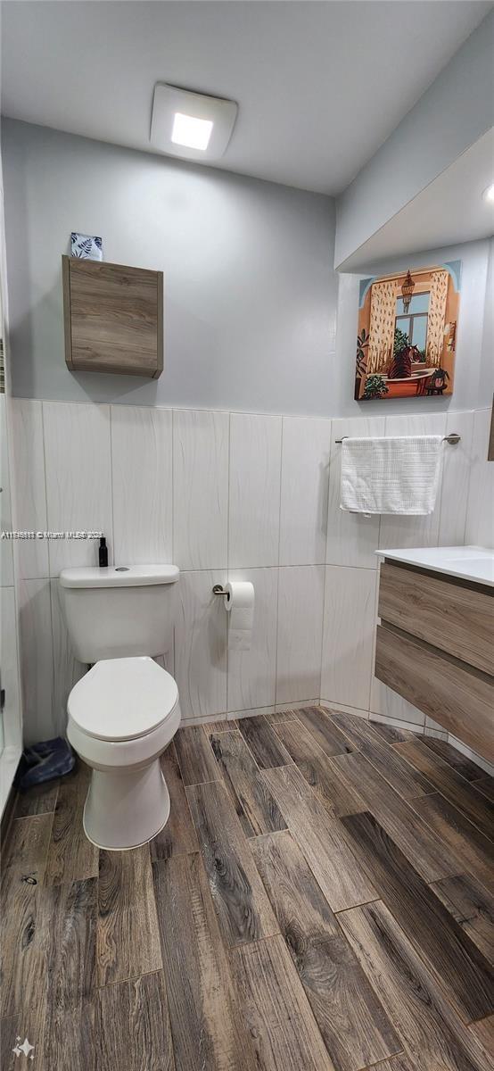 bathroom featuring vanity, toilet, and tile walls