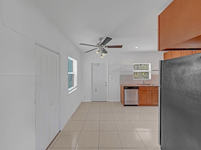 kitchen featuring sink, light tile patterned floors, stainless steel appliances, and decorative backsplash