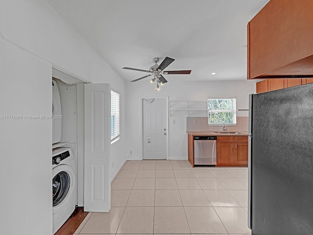 kitchen with sink, appliances with stainless steel finishes, light tile patterned flooring, washer / clothes dryer, and decorative backsplash