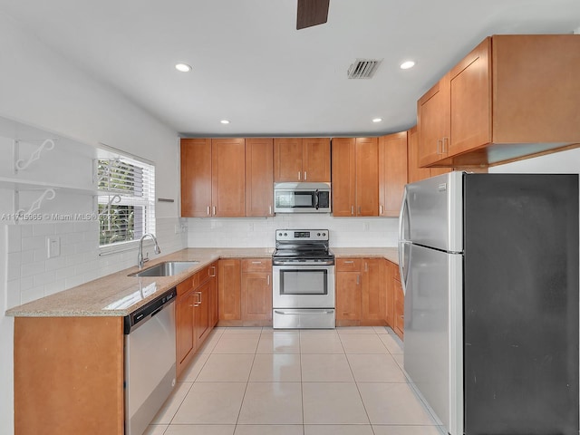 kitchen featuring sink, light tile patterned floors, appliances with stainless steel finishes, light stone counters, and decorative backsplash