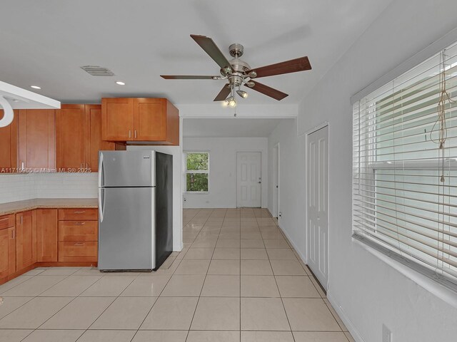 kitchen featuring stainless steel refrigerator, ceiling fan, backsplash, and light tile patterned floors