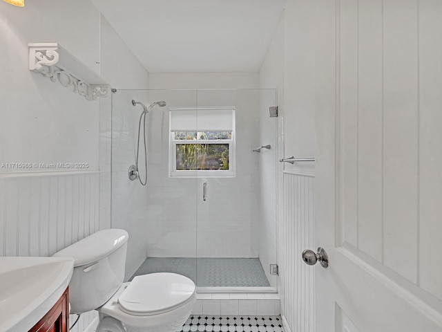 bathroom featuring vanity, a shower with door, and toilet