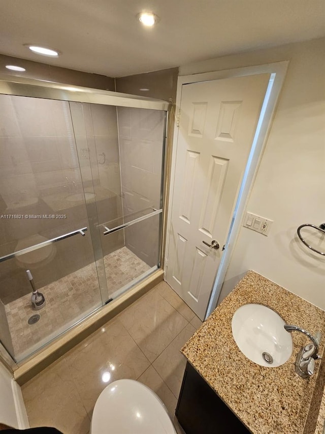 bathroom with tile patterned flooring, vanity, toilet, and a shower with shower door