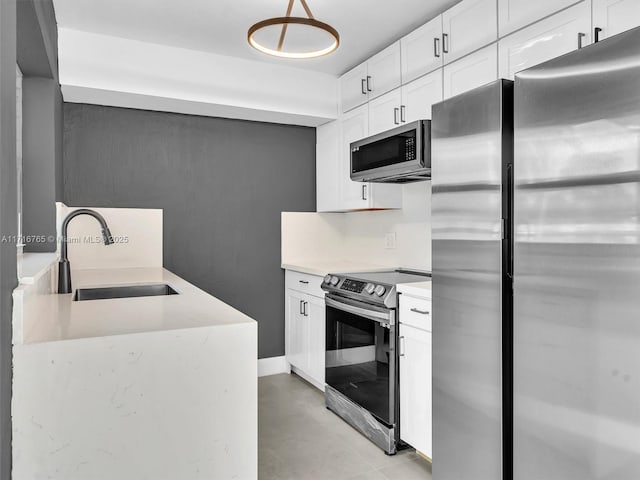 kitchen featuring sink, hanging light fixtures, stainless steel appliances, tasteful backsplash, and white cabinets