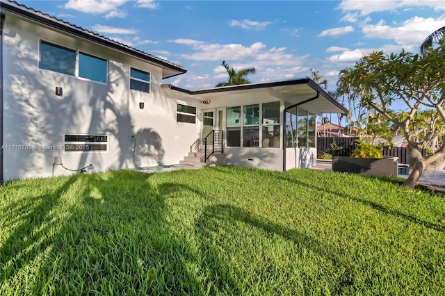 rear view of property featuring a yard and a sunroom