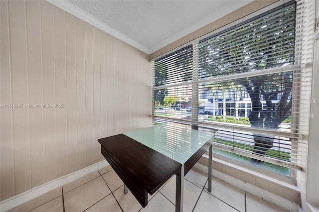 office area featuring wooden walls, crown molding, light tile patterned floors, and a textured ceiling