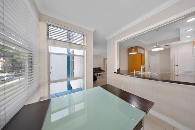 dining space with sink, crown molding, a textured ceiling, a tray ceiling, and light tile patterned floors