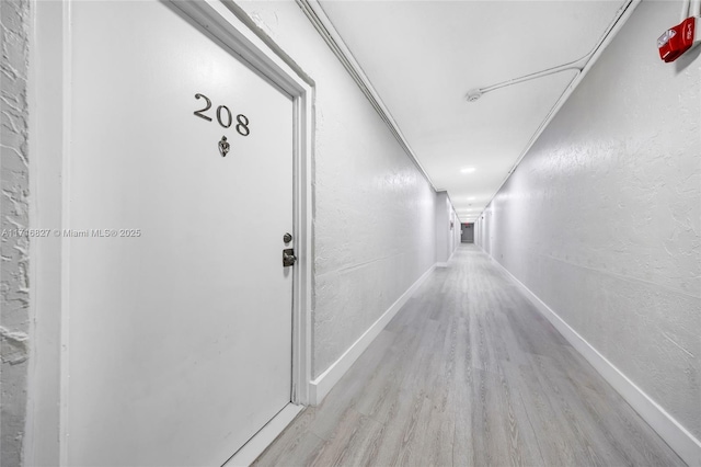 hallway with light wood-type flooring and crown molding